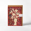 A square greeting card with a kraft envelope behind it, featuring a cream silhouette of a hand holding a flower branch over a red floral pattern background. A small white paper label on the right reads 'Handmade' and 'The Art of Cards'.
