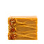 Three bars of orange soap with visible seeds on a white background