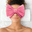 Person wearing a pink eye mask with a large bow on a white background