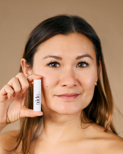 model holding lip balm to her face