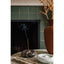 Incense burner with smoke in front of a fireplace, next to a vase with orange berries.