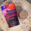 Grahams Hot Chocolate Flakes packaging with a mug of hot chocolate on a wooden surface
