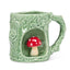 Green ceramic mug shaped like a tree with a red mushroom inside on a white background