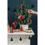 Decorative Christmas tree with ornaments on a mantelpiece against a dark blue wall.