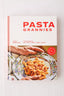 A spiral-bound cookbook titled 'Pasta Grannies' by Vicky Bennison, featuring a white cover with red lettering and a photo of pasta on a patterned plate. The book is photographed standing upright against a light textured background.