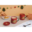 Two red mugs with fairy designs on a table with cookies and a plate, against a festive background.
