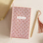 Decorative notebook with floral pattern and 'Knowledge is power' quote, accompanied by a pen on a light background.