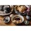 Bowl of cream with jam, scones, and tea on a wooden table