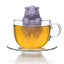 Hippo-shaped tea infuser in a glass of tea on a white background