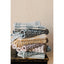 Stack of folded towels in various patterns and colors on a wooden surface with a beige wall background.