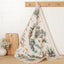 Tea towel with nature-themed design hanging on a wooden rack.