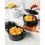 Two black cast iron pots with mac and cheese on a white surface, one pot being opened.
