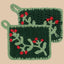 Two green crocheted pot holders with red flowers on a white background